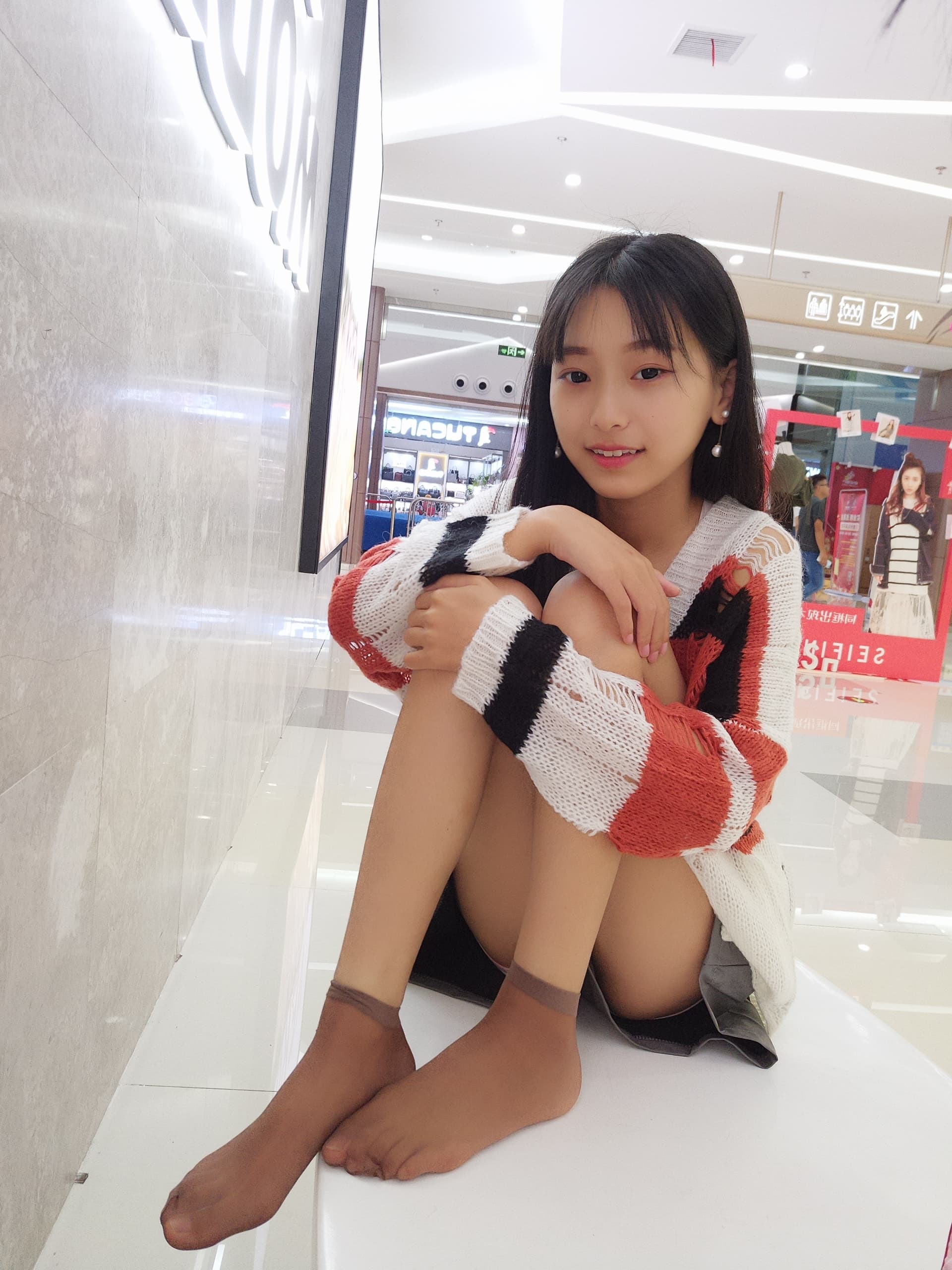 Close view of ankle and bare foot near a store window, stocking edge and urban reflections
