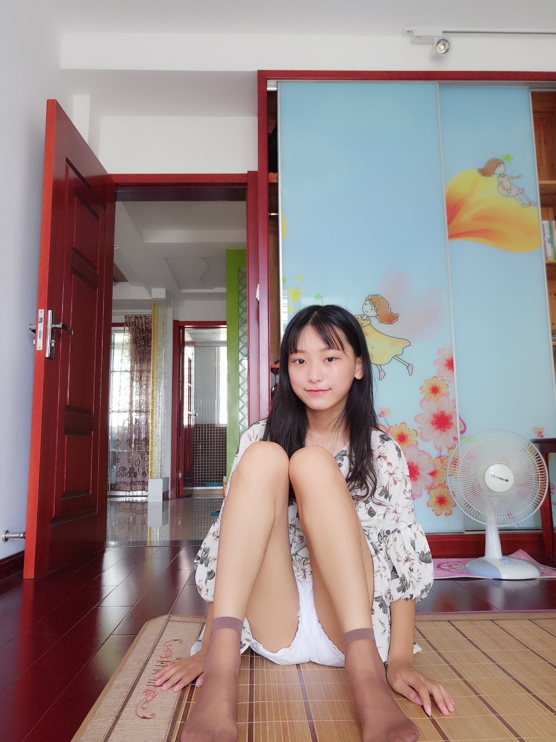 Close-up of ankle and foot in short stocking, floral skirt fabric brushing the skin, moody tones