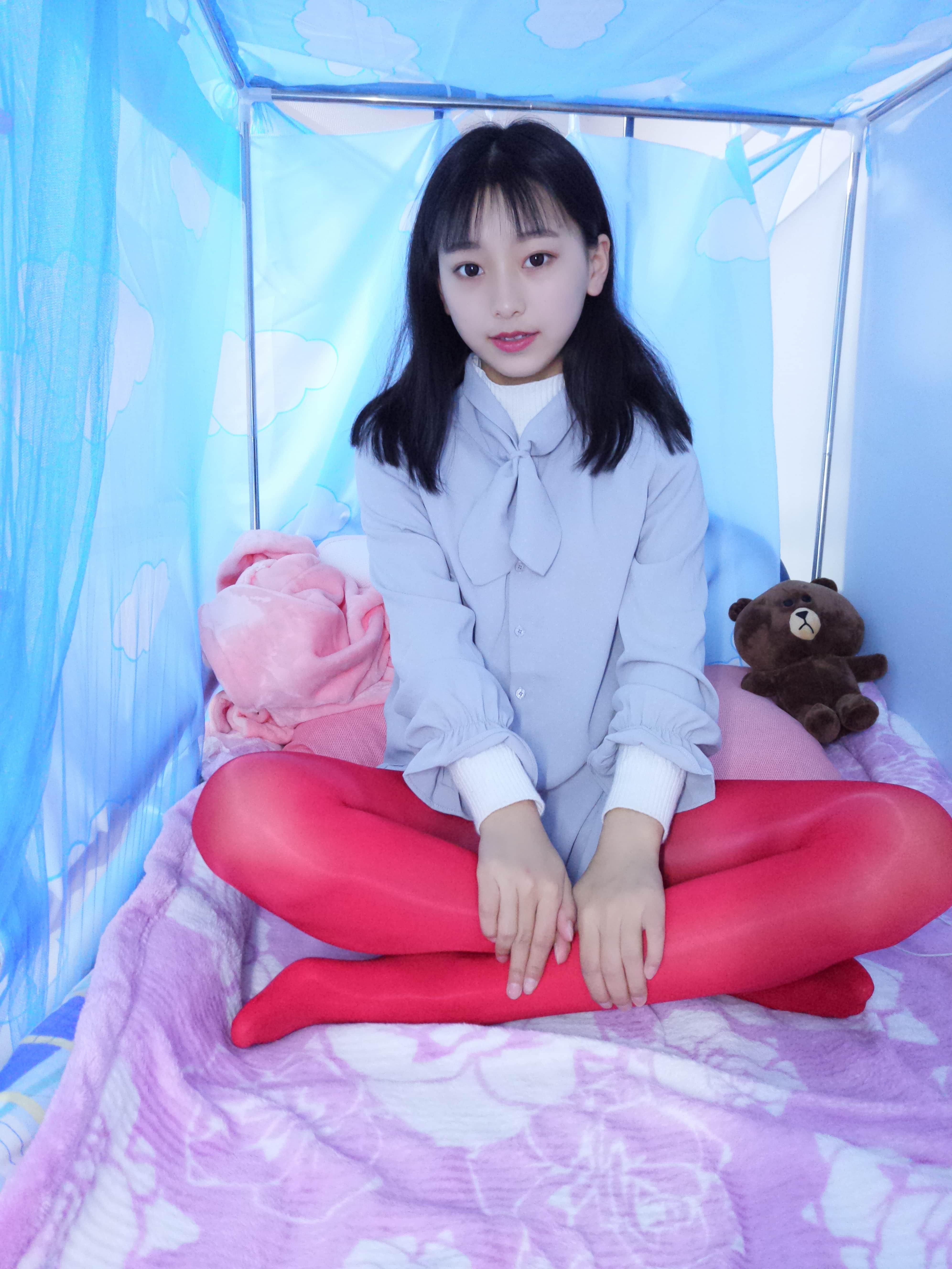 Detail shot of glossy red hosiery and exposed heels, feet posed alluringly on rumpled linens.