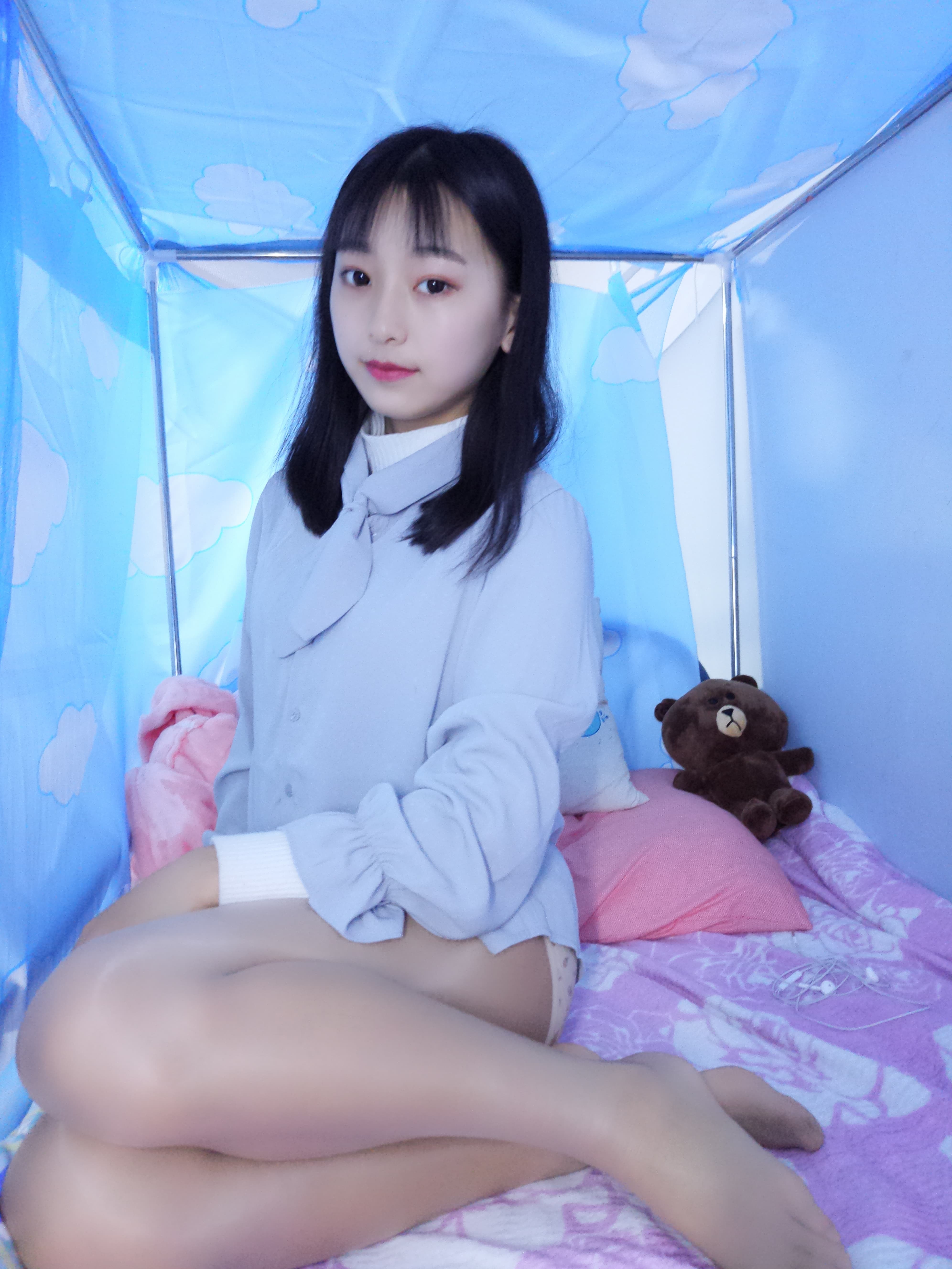 Intimate close-up of feet in shiny nylon stockings with white panties in frame, toes pressing into soft sheets.