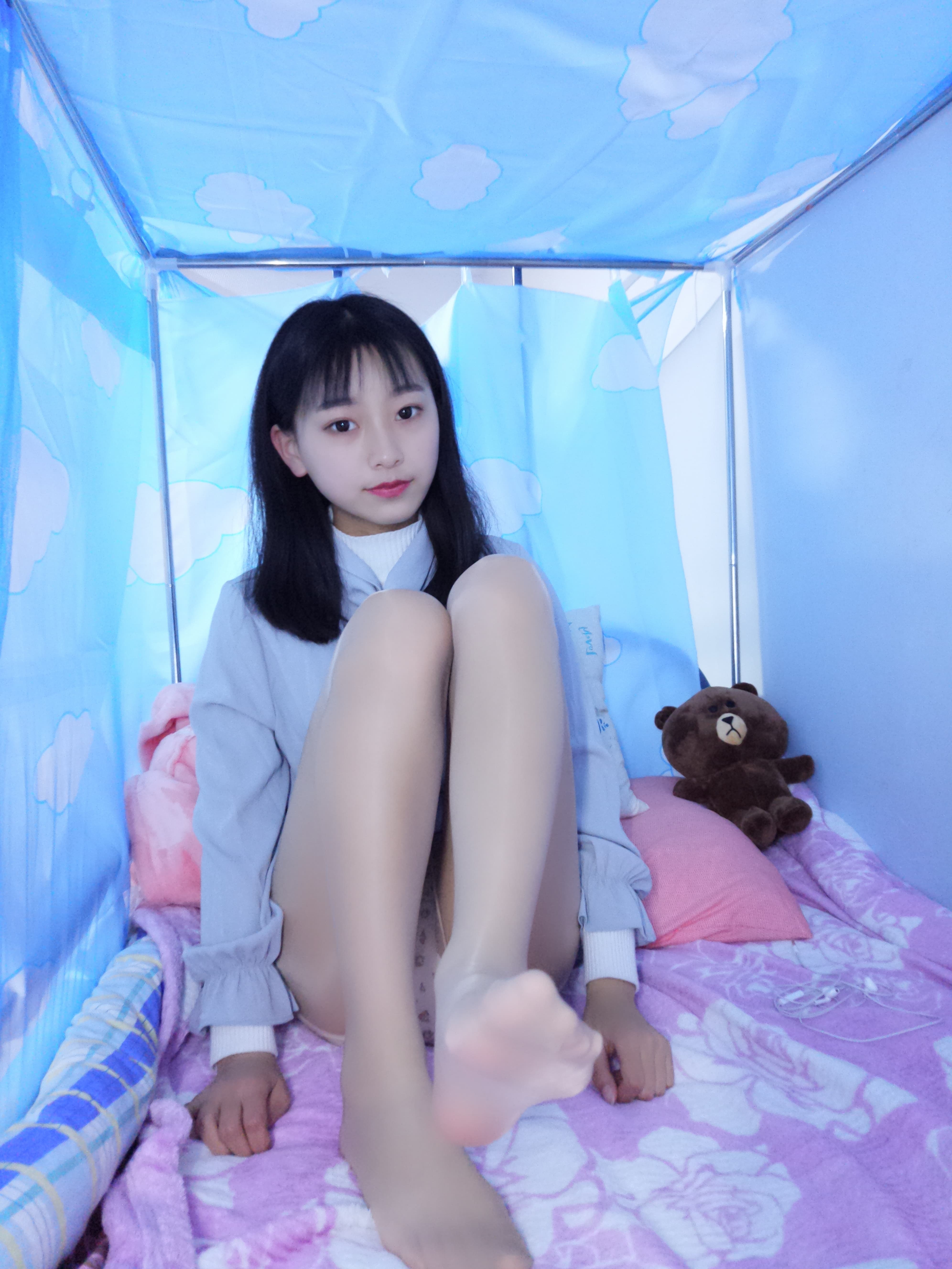 Low-angle shot of glossy stockings and white panties, showcasing arched soles and gentle calf contours on the bed.