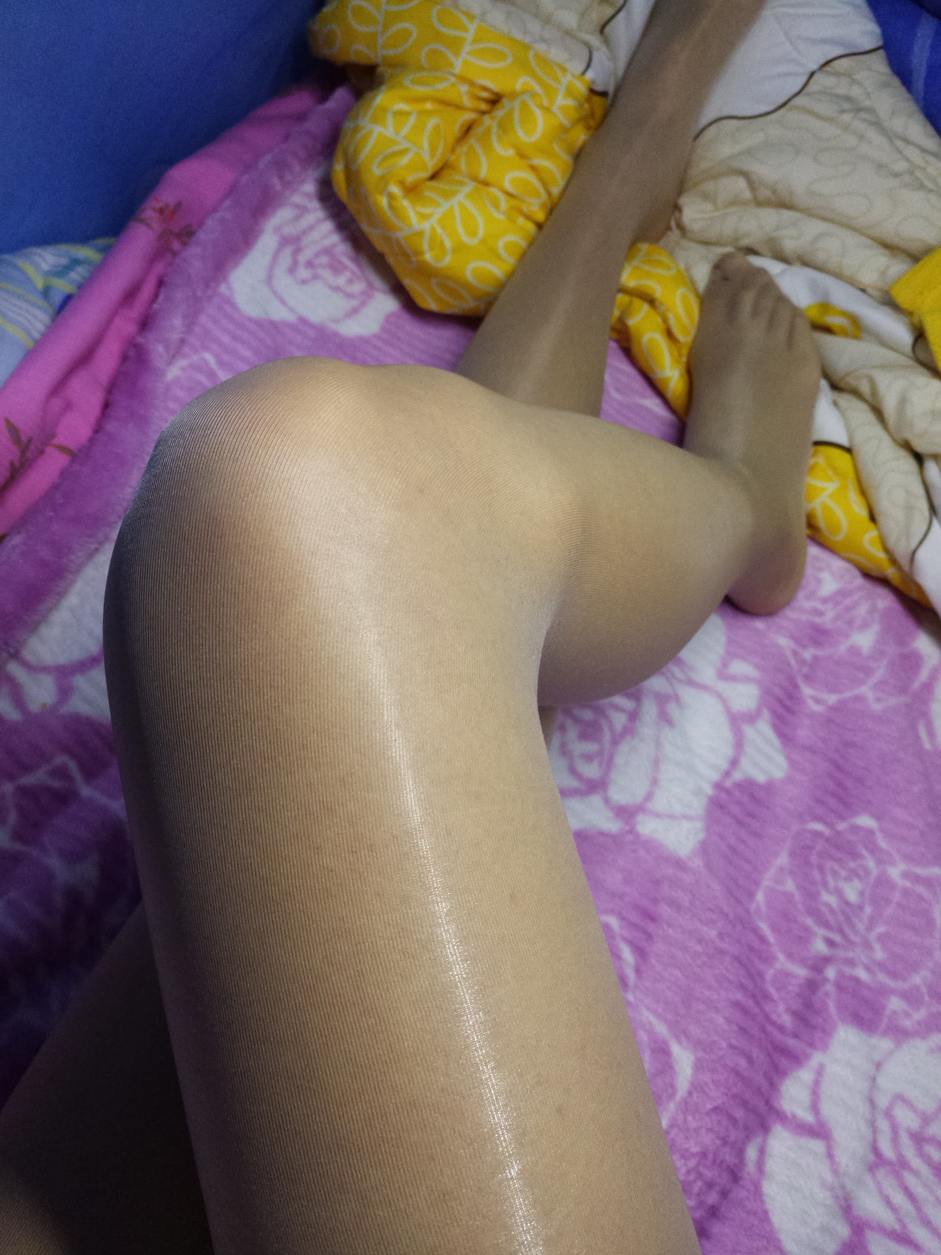 Intimate portrait of dark-skinned legs in sheer tights, close focus on the arch and toes with nylon sheen against the skin.