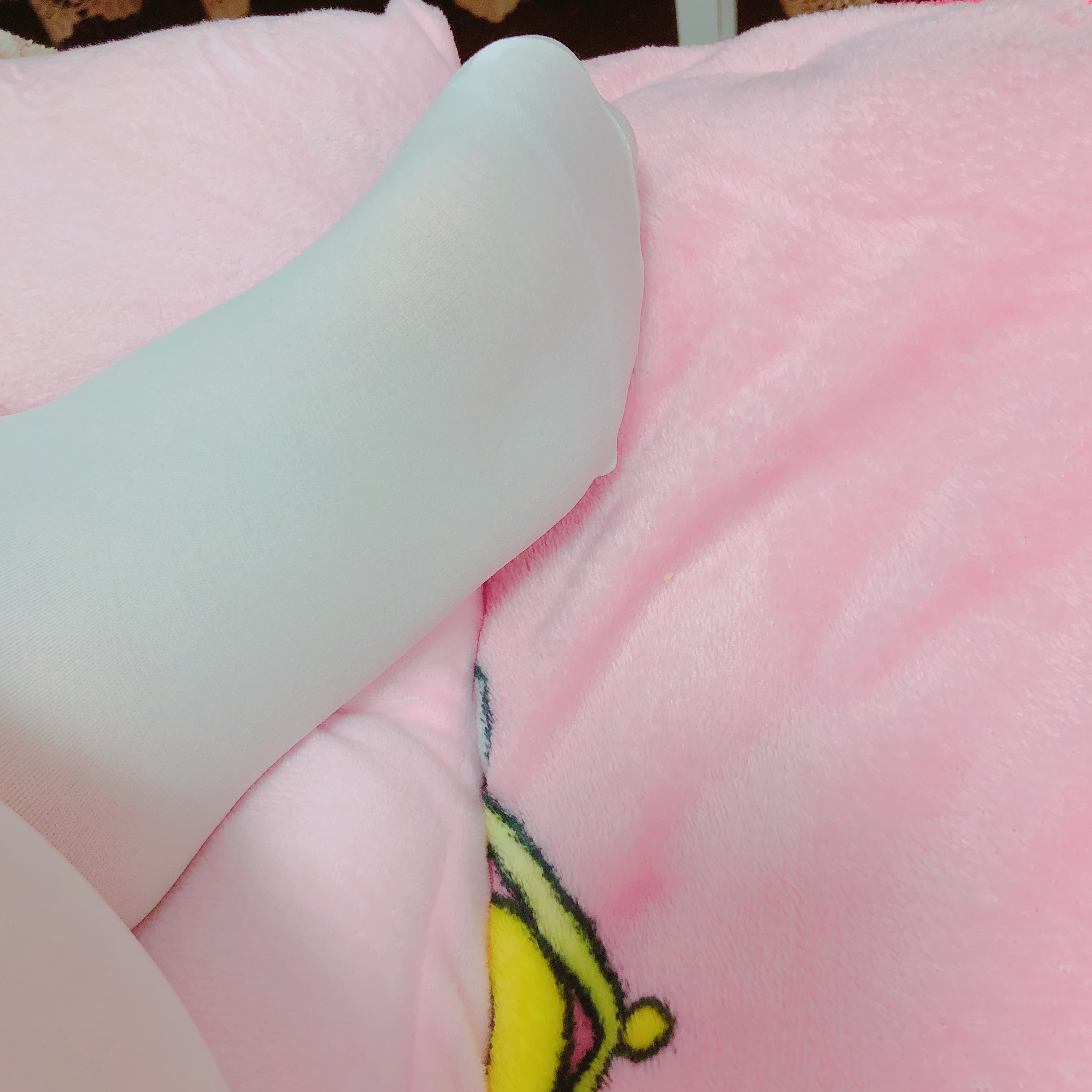 Close-up of white socked feet curled on a soft blanket, toes slightly visible and inviting touch