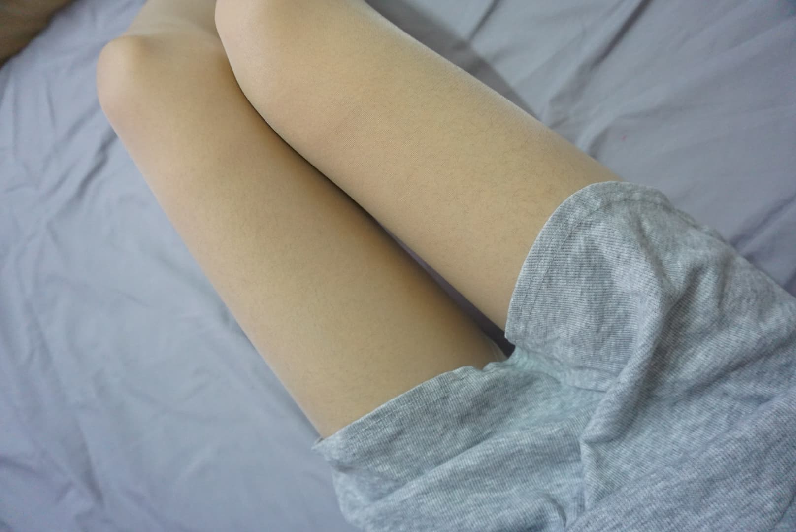 Detail of a white nylon-clad foot lifting from the floor, subtle wrinkles at the heel and delicate toe definition visible.