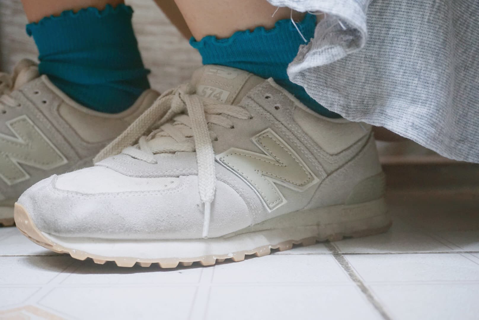 Lifestyle shot of sneakers on a doorstep, blue socks peeking out above collars, worn creases and casual, cozy atmosphere.