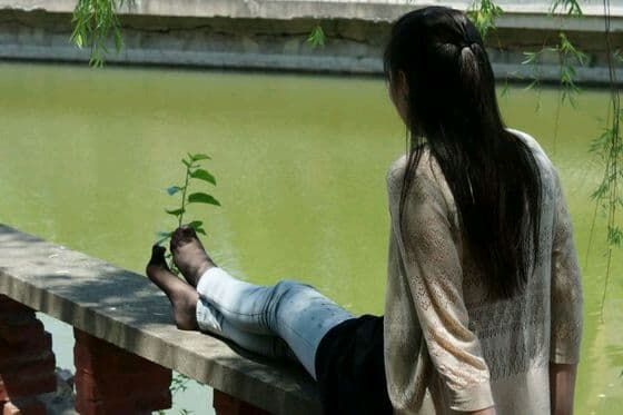 Portrait of a mature woman modeling sheer pantyhose with soft cotton socks layered over them, crossed legs and teasing pose