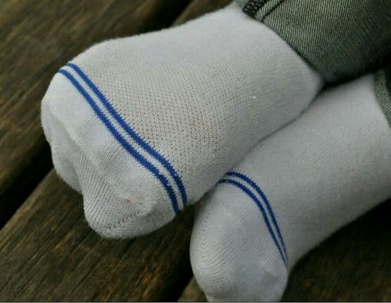 Street-style shot of a young woman in a short skirt, cozy cotton socks pulled high, bare ankles hinting flirtatiously