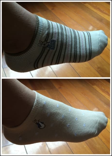 Folded cotton sock on a wooden floor beside slippers, hinting at recent wear and lingering scent.