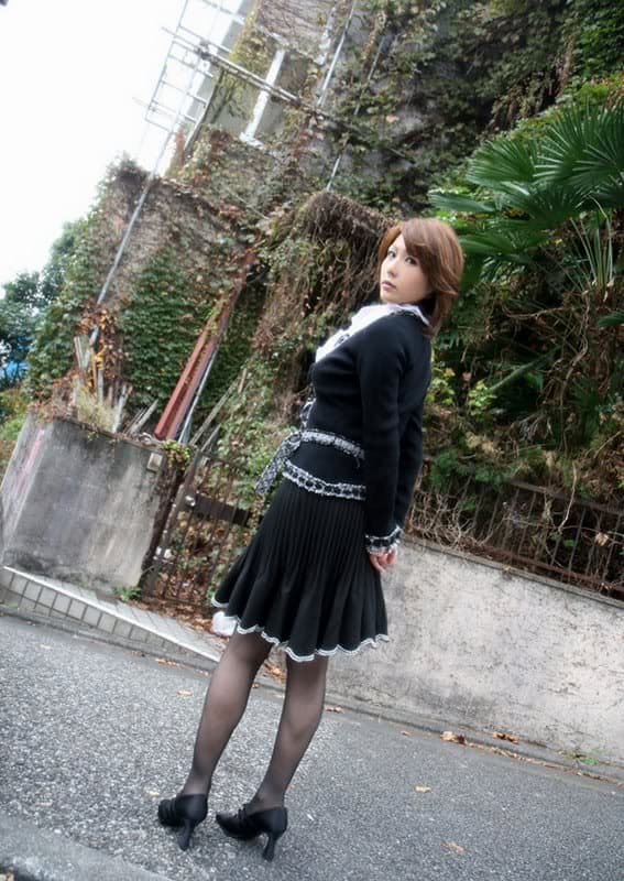 Mature woman crossing city street in sheer black stockings, highlighting glossy nylon sheen and graceful leg silhouette in natural light