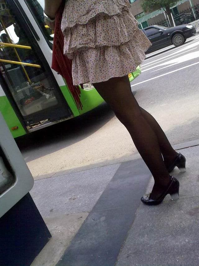 Candid image of a woman laughing while wearing sheer black stockings, leg extended and light catching the nylon surface