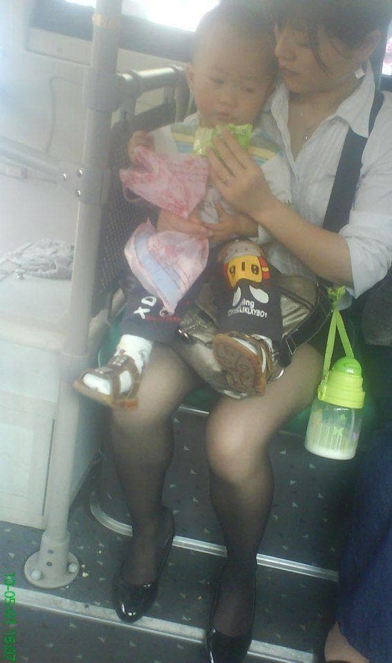 Woman in black stockings seated on a bus beside her partner, sheer nylon hugging her calves and ankles.