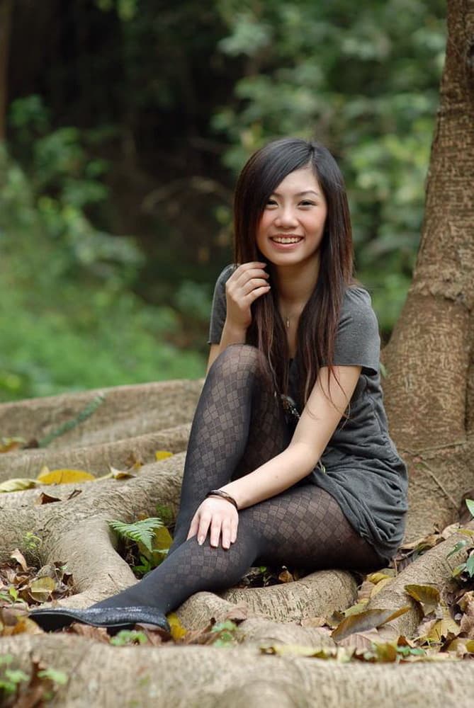 Close up of patterned stockings hugging a crossed leg, nylon sheen and delicate lace detail in soft light.