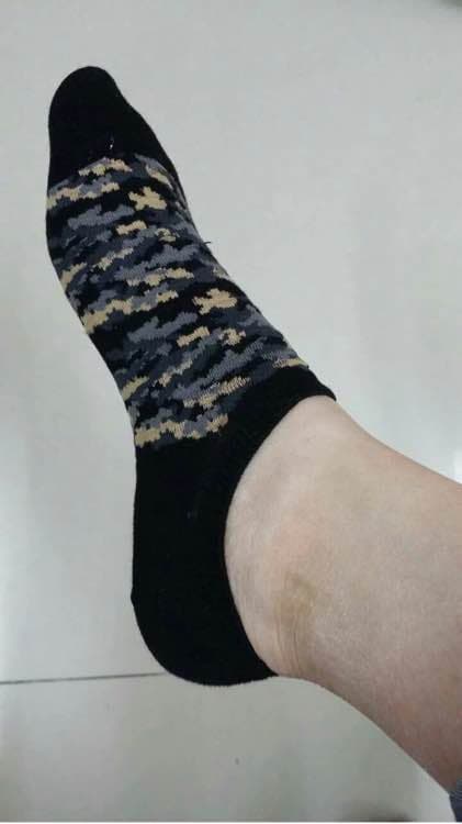 Model sits on a low step, shoes discarded, one cotton sock peeled down to reveal a soft arch and curled toes