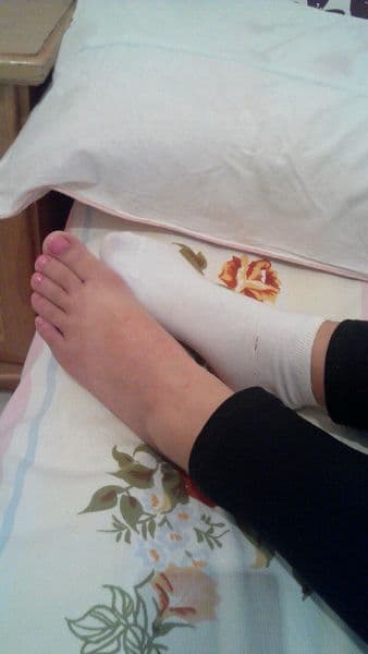 Hand slipping down soft cotton sock to reveal a freshly freed bare foot with warm sole