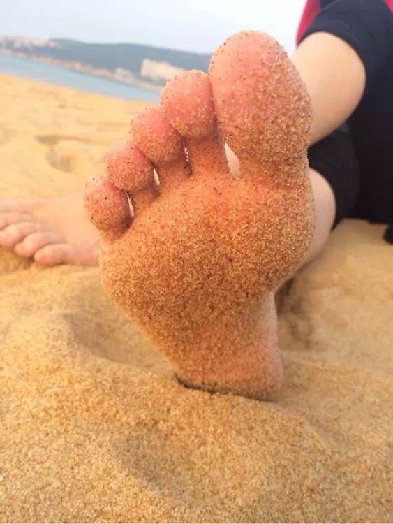 Sunlit beach close-up of soles pressed into warm sand with toes spread