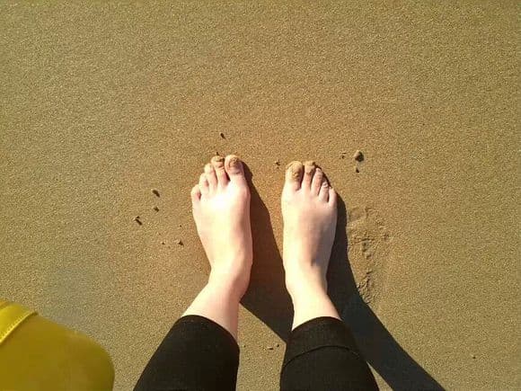 Natural foot portrait from a real shoot, bare sole and ankle lit softly with candid, lived-in texture