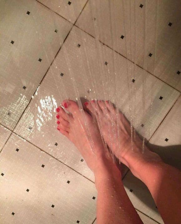 Moist foot close-up with droplets on the skin, nylons clinging and highlighting the curve of the arch