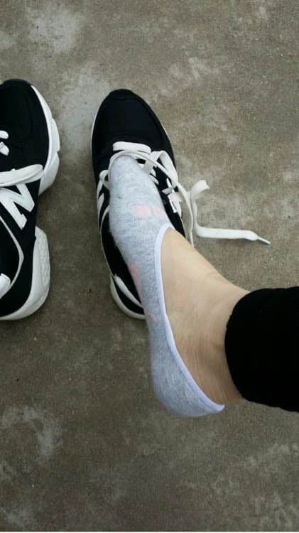 Woman slipping off shoes to show clean white boat socks and exposed ankles in warm indoor lighting