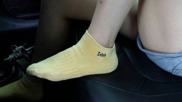 Bright yellow boat socks on a relaxed foot, showing ankle exposure and fabric stretching over toes
