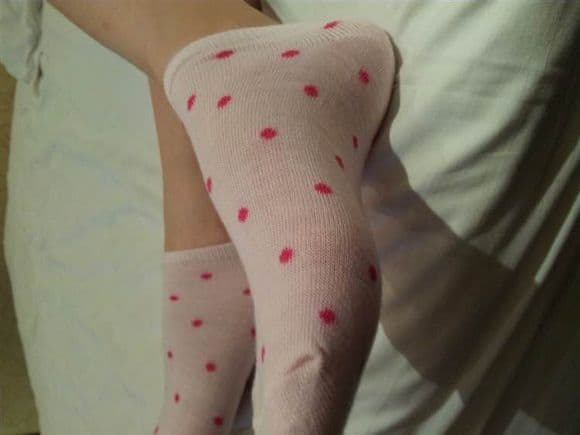 Pink boat socks with round patterns hugging a bare ankle, soft pastel tones and fabric detail