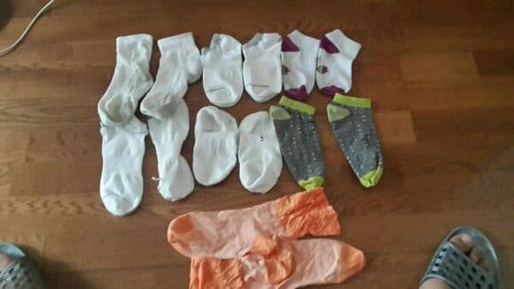 Assortment of boat socks scattered on a sofa, varying wear levels and textures, warm home lighting.