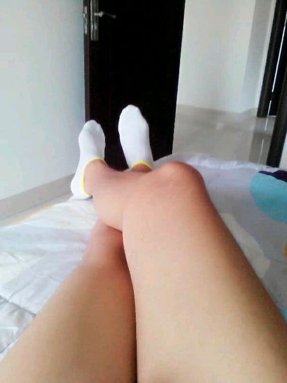 Close-up of pale thighs with white boat socks and smoothed nylon sheen on exposed skin