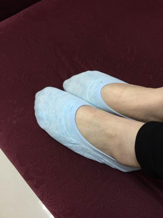 Worn socks folded near bare feet, hinting at lingering scent and textured cotton surface.