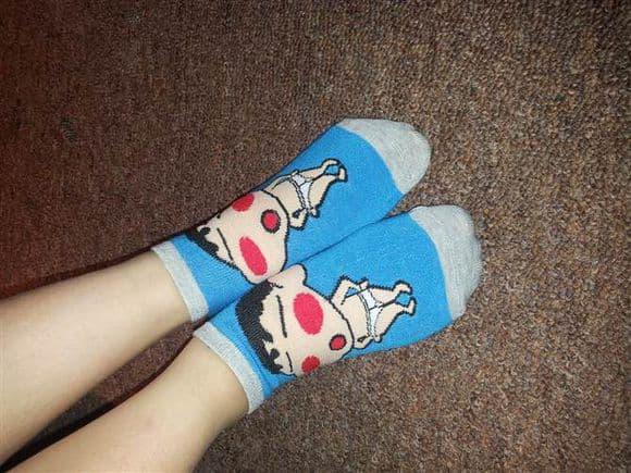 Bright patterned socks half-rolled down, revealing supple ankle and a hint of nylons underneath.