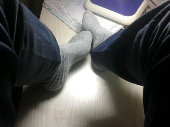 Pile of assorted cotton socks with a focus on soft gray pairs covering small feet, ribbed texture and light wear visible