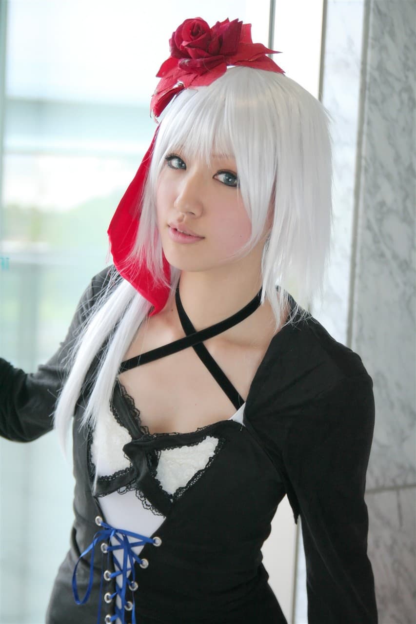 White-haired model seated with crimson thigh-highs, lace trim and glossy nylon emphasized against pale skin and dark backdrop