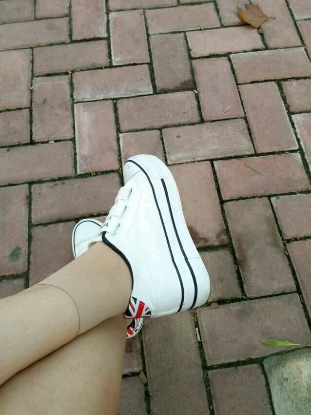 Short sheer stockings peeking above low canvas sneakers with playful toe movement