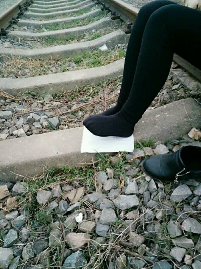 Outdoor close-up of feet in short stockings, stockings cuffed at ankle with dust and sunlight highlighting skin texture