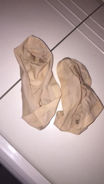 Close-up of petite bare feet slipping from worn cotton socks, toes slightly curled and skin softly glowing under warm light