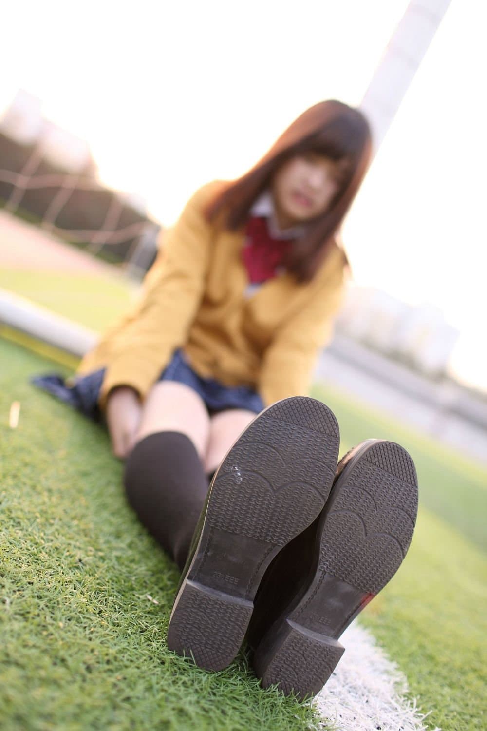 Anonymous cosplayer’s lower body shot focusing on stockinged feet and folded socks on wooden floor