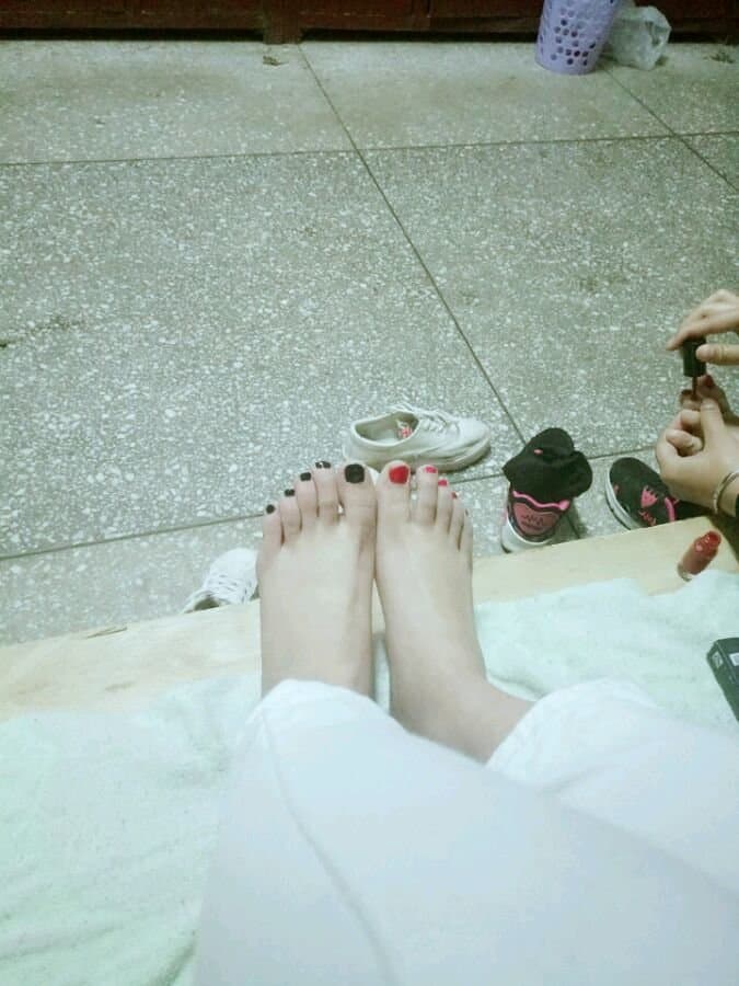 Elegant young woman reclining with bare jade-toned feet prominently displayed against silk sheets