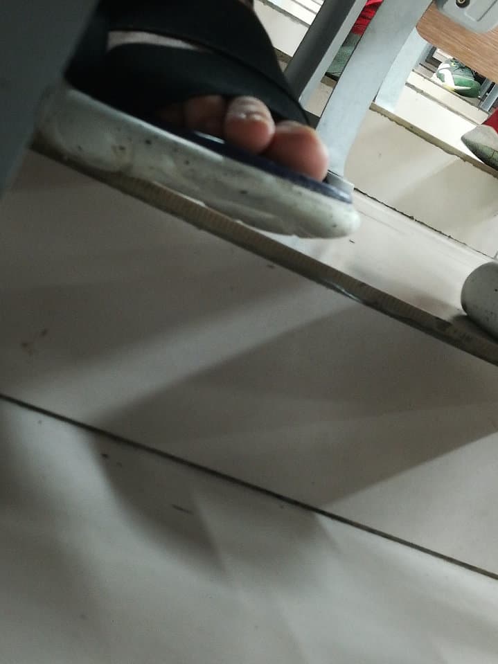 Candid shot of a peer’s bare sole peeking from beneath a desk with stocking edge visible