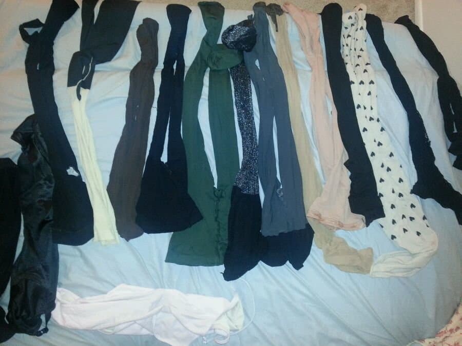 Playful shot of adult model laughing while peeling off damp stockings, bare feet flexing and toes wiggling on a cool tile floor.