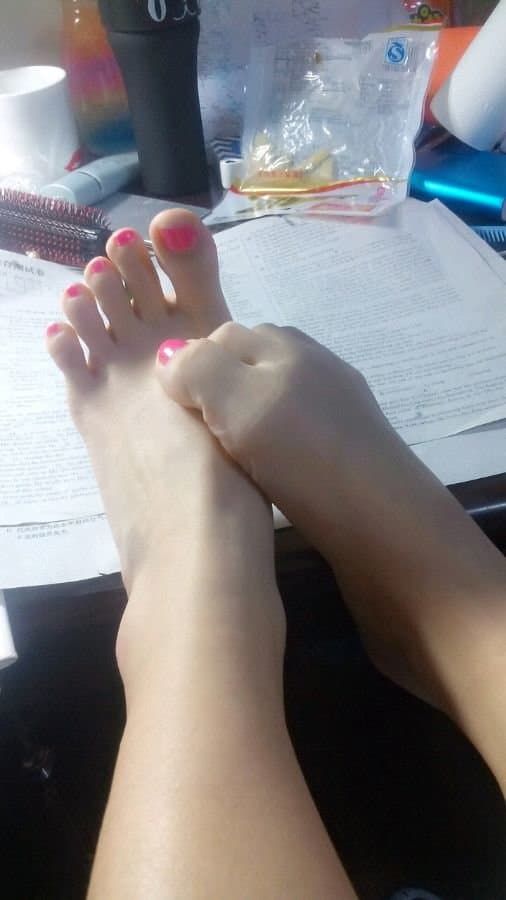 An identifiable arch and ankle in soft shadow, stocking edge rolled down slightly, intimate adult foot portrait