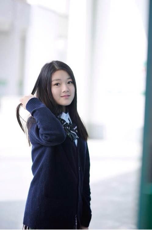 Adult model in plaid skirt adjusting thigh-high stockings, kneeling with bare soles visible beneath sporty sneakers