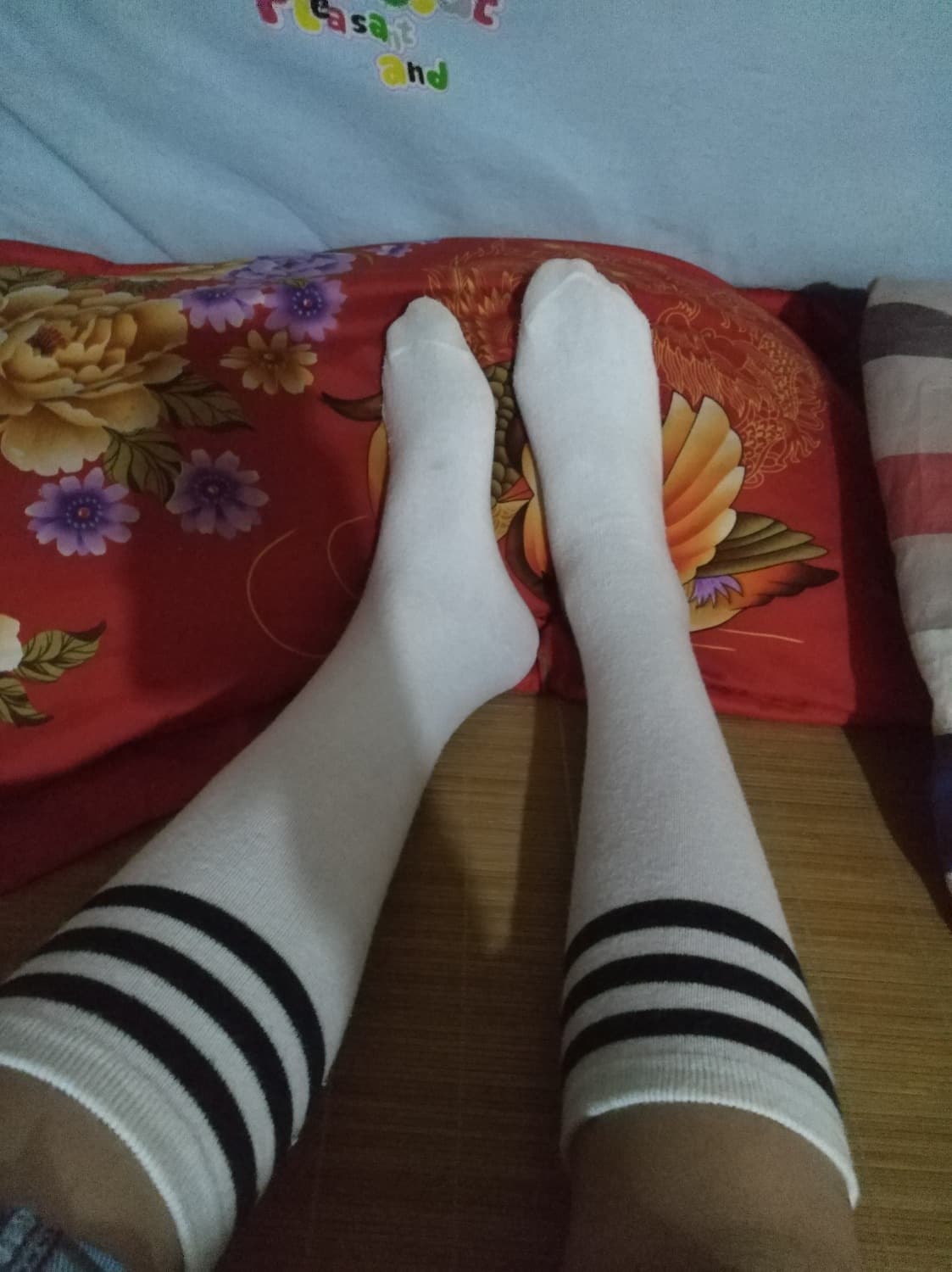 Stocking-clad feet with one stocking rolled down, toes peeking as she playfully teases the viewer in soft light