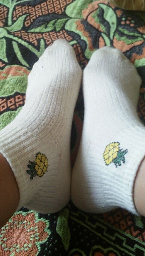 Close view of painted toes emerging from glossy nylon stockings, foot resting against smooth fabric for contrast