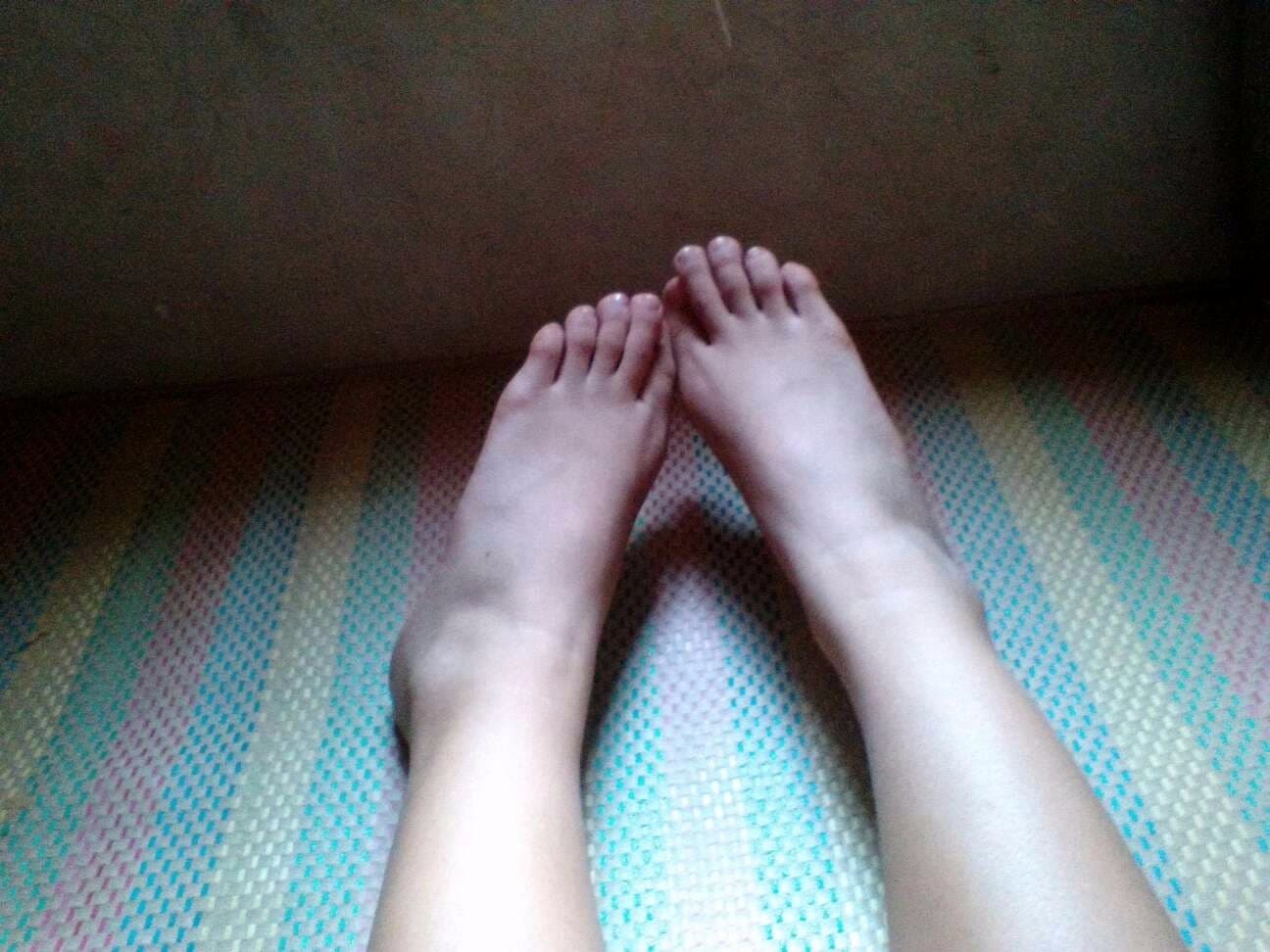 High-angle view of stocking-clad foot resting on linen, toes gently flexed beneath translucent nylon.