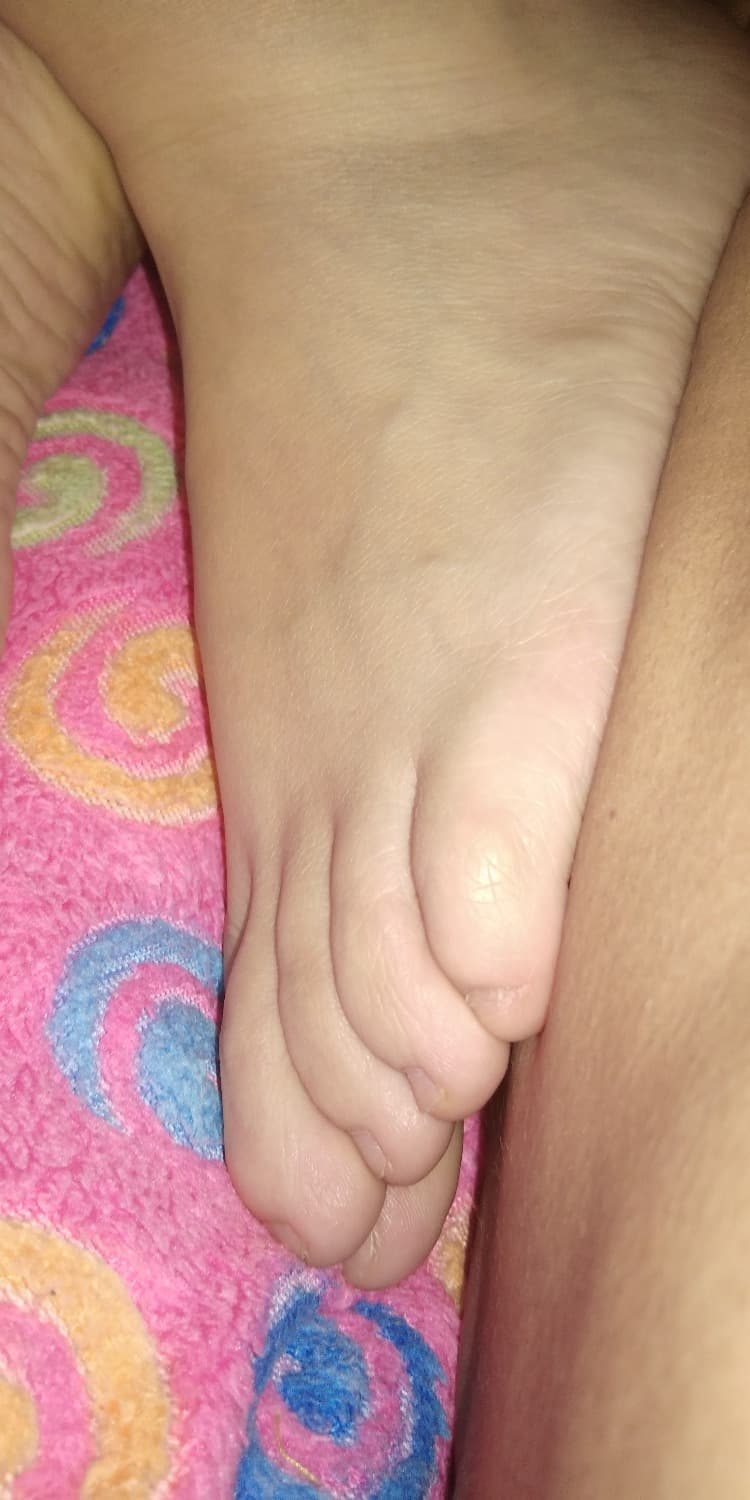 Playful scene of a foot being slipped from nylons, close framing showing ankle, toes, and the intimate motion of undressing