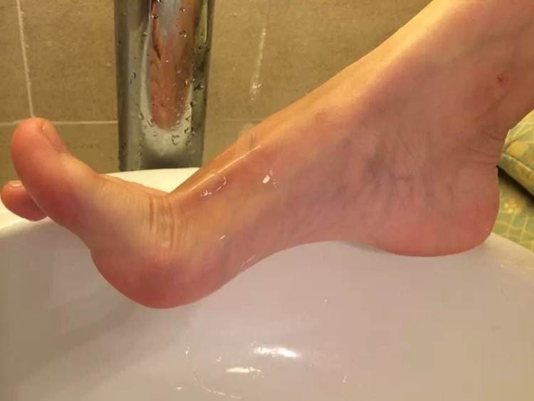 Wide shot of a plush sofa cradling bare and stockinged feet, cushions shaped by warm contours.