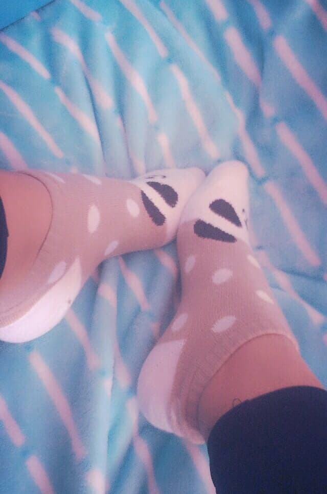 Panda-patterned sock sliding down a foot, soft plush detail and bare heel peeking through