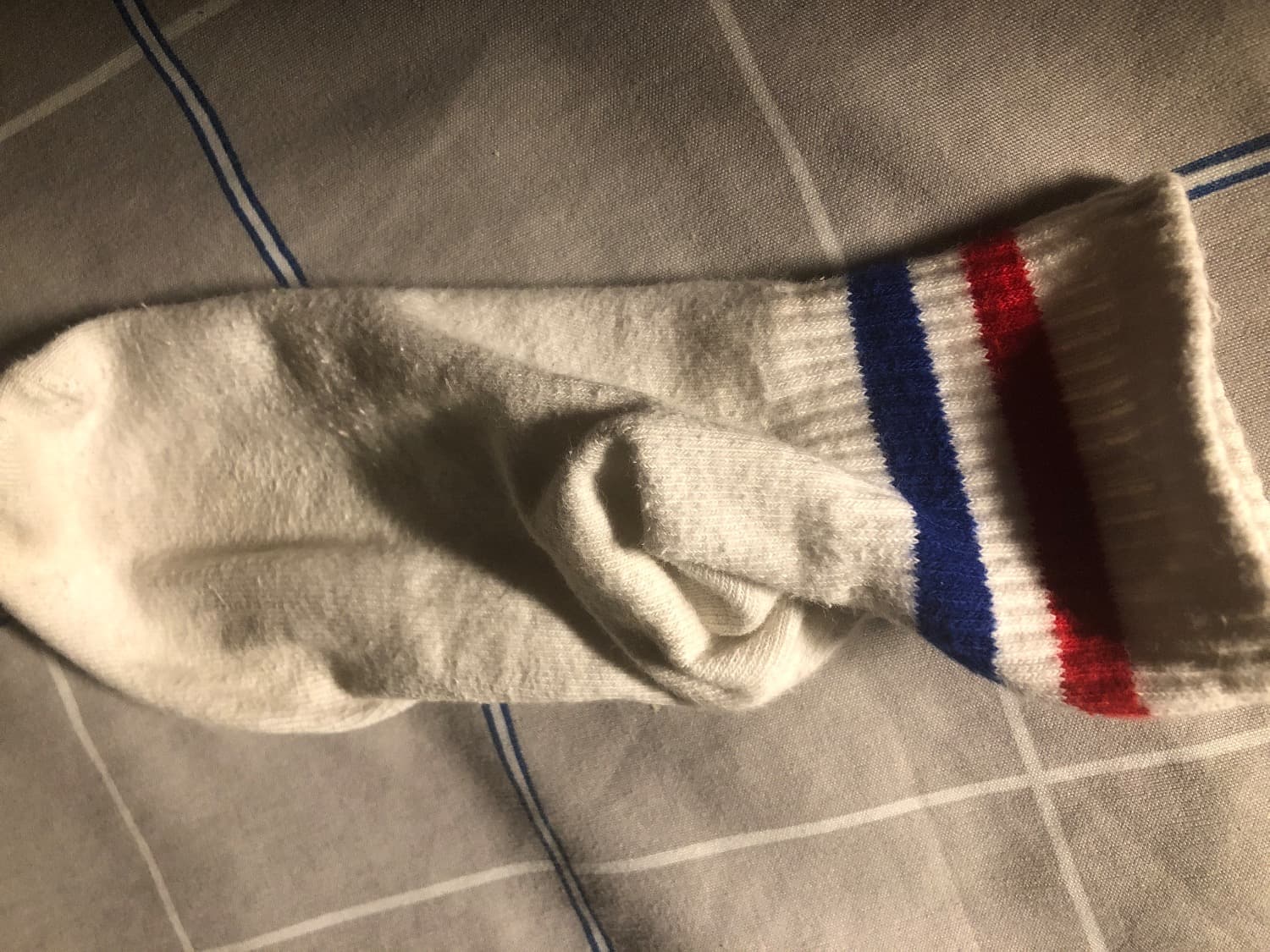 Close-up of slightly worn white cotton socks resting on a pillow, hint of foot shape visible