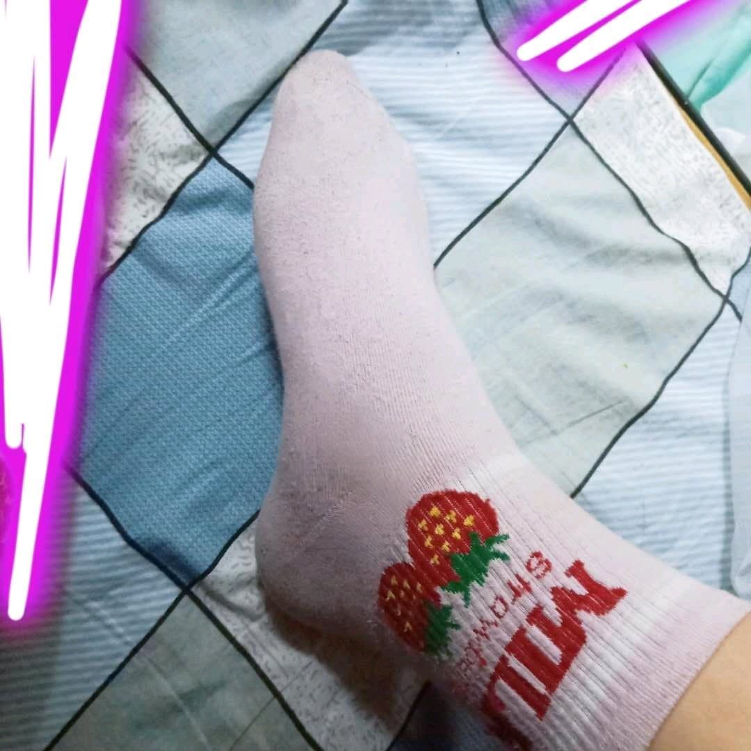 Pair of short white cotton socks on bare feet, ankle exposed, photographed with soft focus and cozy indoor lighting