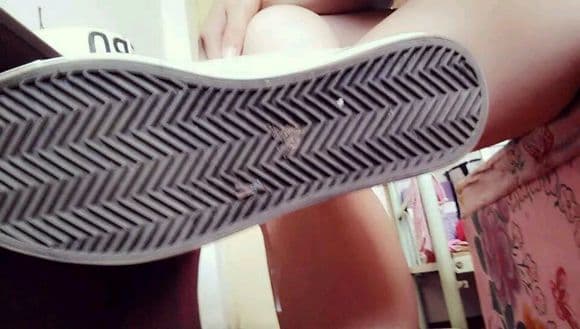 Feet in short black stockings paired with worn canvas shoes, contrast between sheer fabric and textured shoe surface clearly visible.