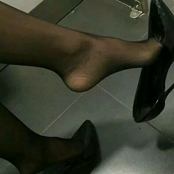 Close up of glossy silk stocking hugging the arch and toes, soft sheen highlighting skin texture and gentle creases.