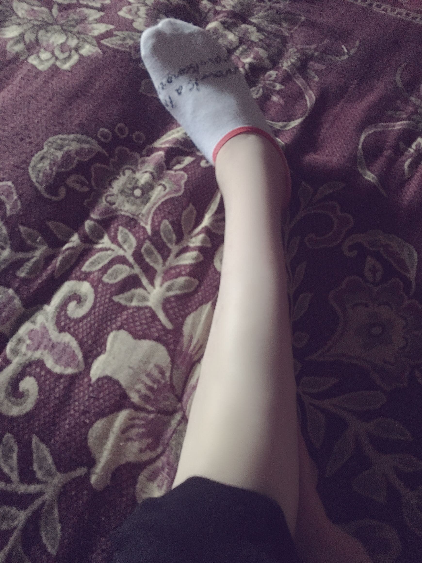 Two pairs of feet near a casually discarded sock, one person inhaling while the other watches with a smile